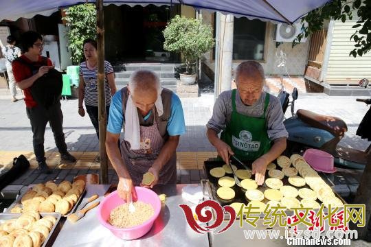 图为老哥俩在街边自制“土月饼”。 张远 摄 图为老哥俩在街边自制“土月饼”。 张远 摄